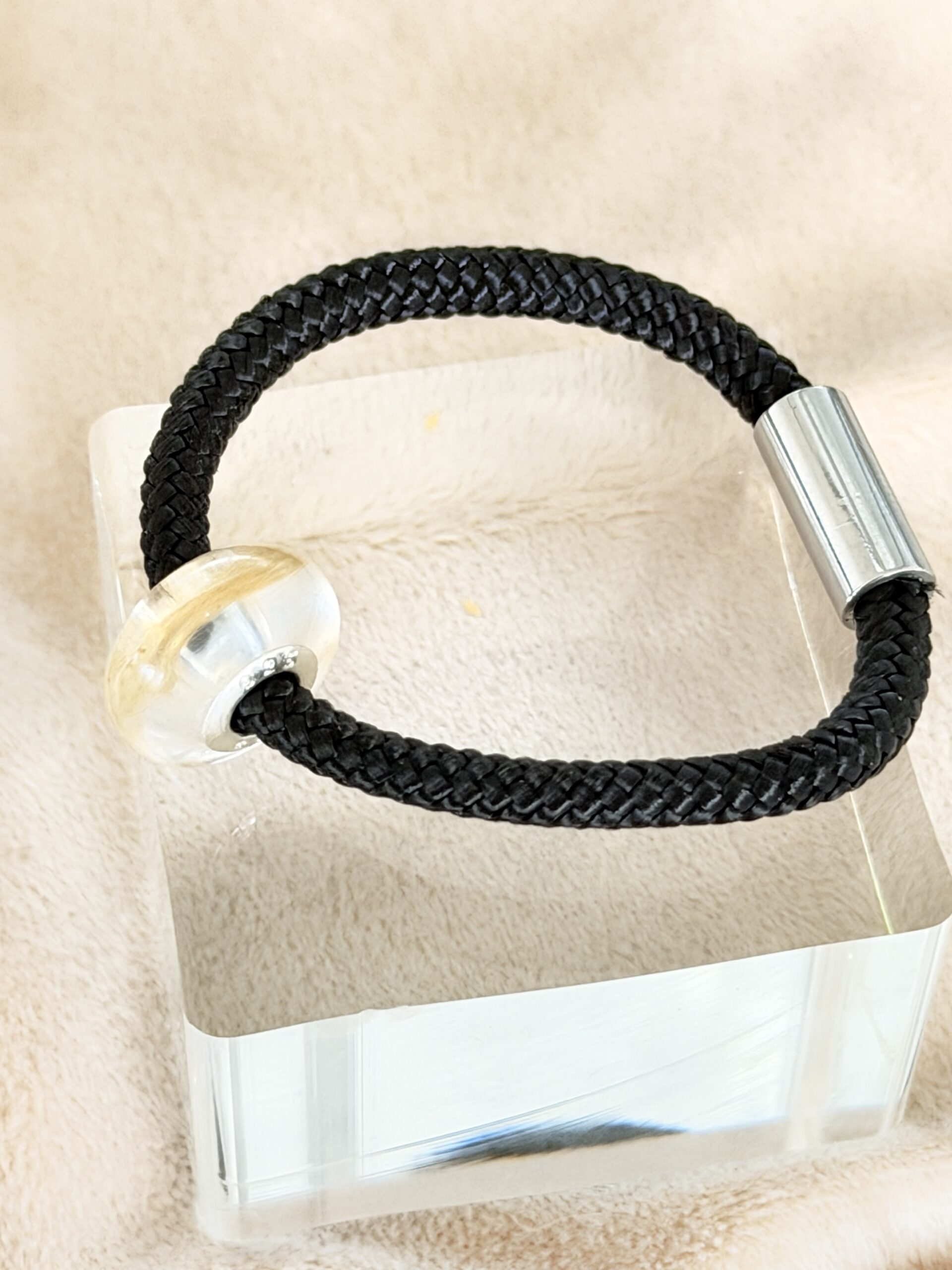 Detailaufnahme der Epoxidharz-Kugel des Segeltau Armbands mit Pfote. Sichtbar eingearbeitetes Tierfell bzw. Stoff vom Geschirr. Handgefertigter Erinnerungsschmuck.