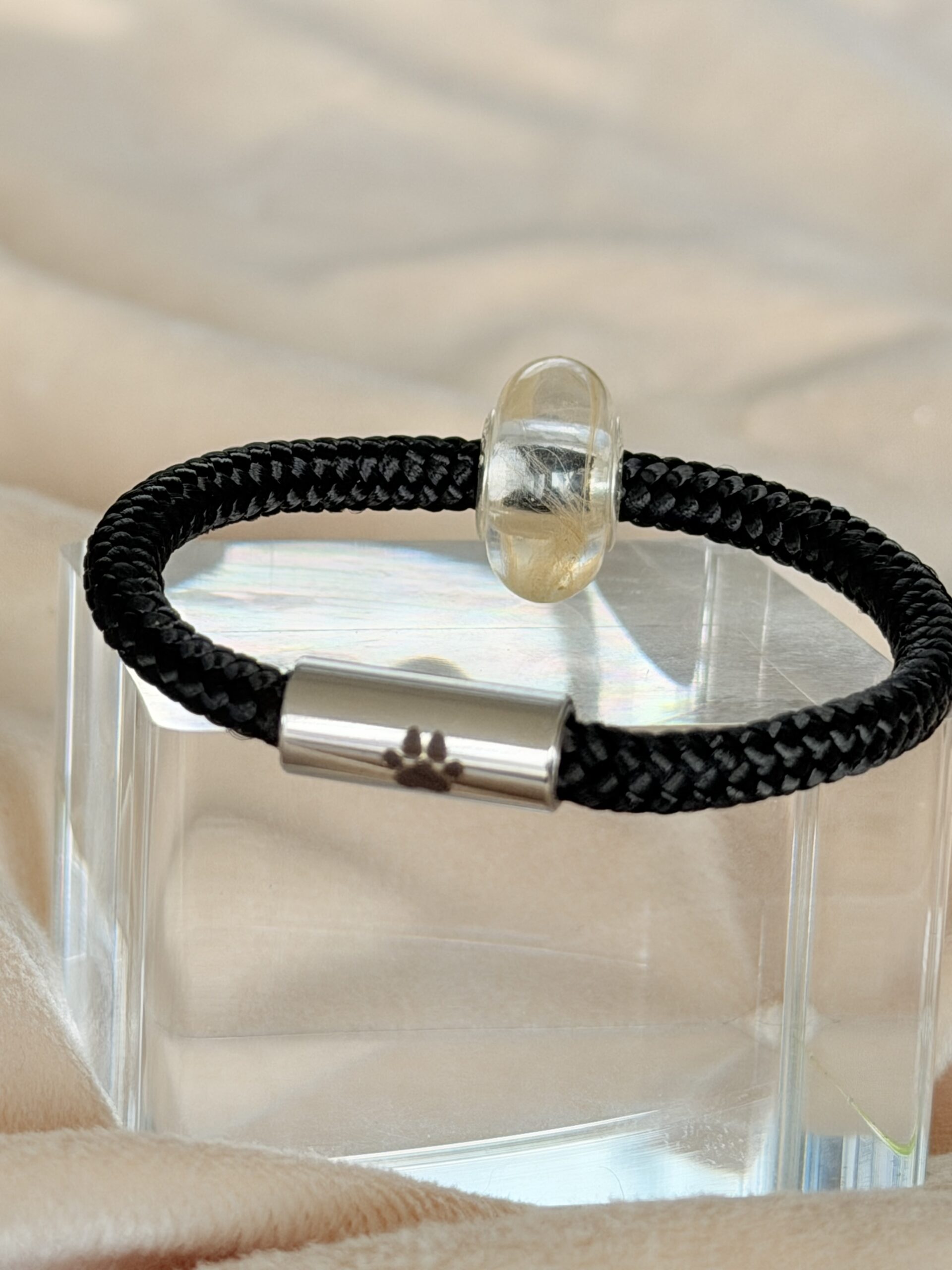Segeltau Armband mit Pfote und Erinnerungskugel aus Epoxidharz. In der Harzkugel ist Fell oder Stoff eines Tieres eingearbeitet. Edelstahlverschluss mit Pfoten-Gravur. Handgefertigtes Erinnerungsarmband in verschiedenen Farben und nach Maß gefertigt.